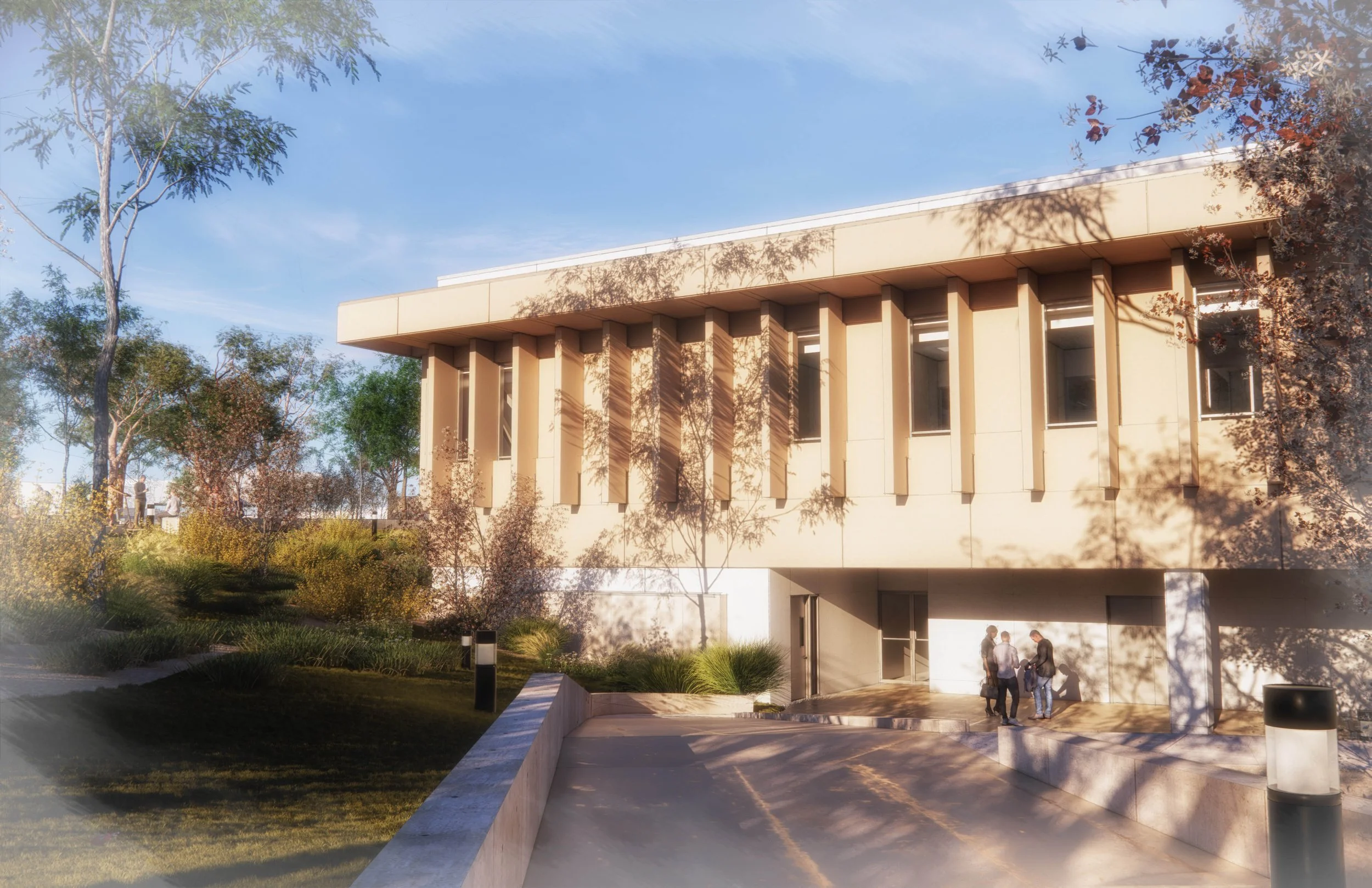 Modern university or office building with a beige facade, tall narrow windows, surrounded by landscaped greenery, with three people walking at the entrance on a sunny day.