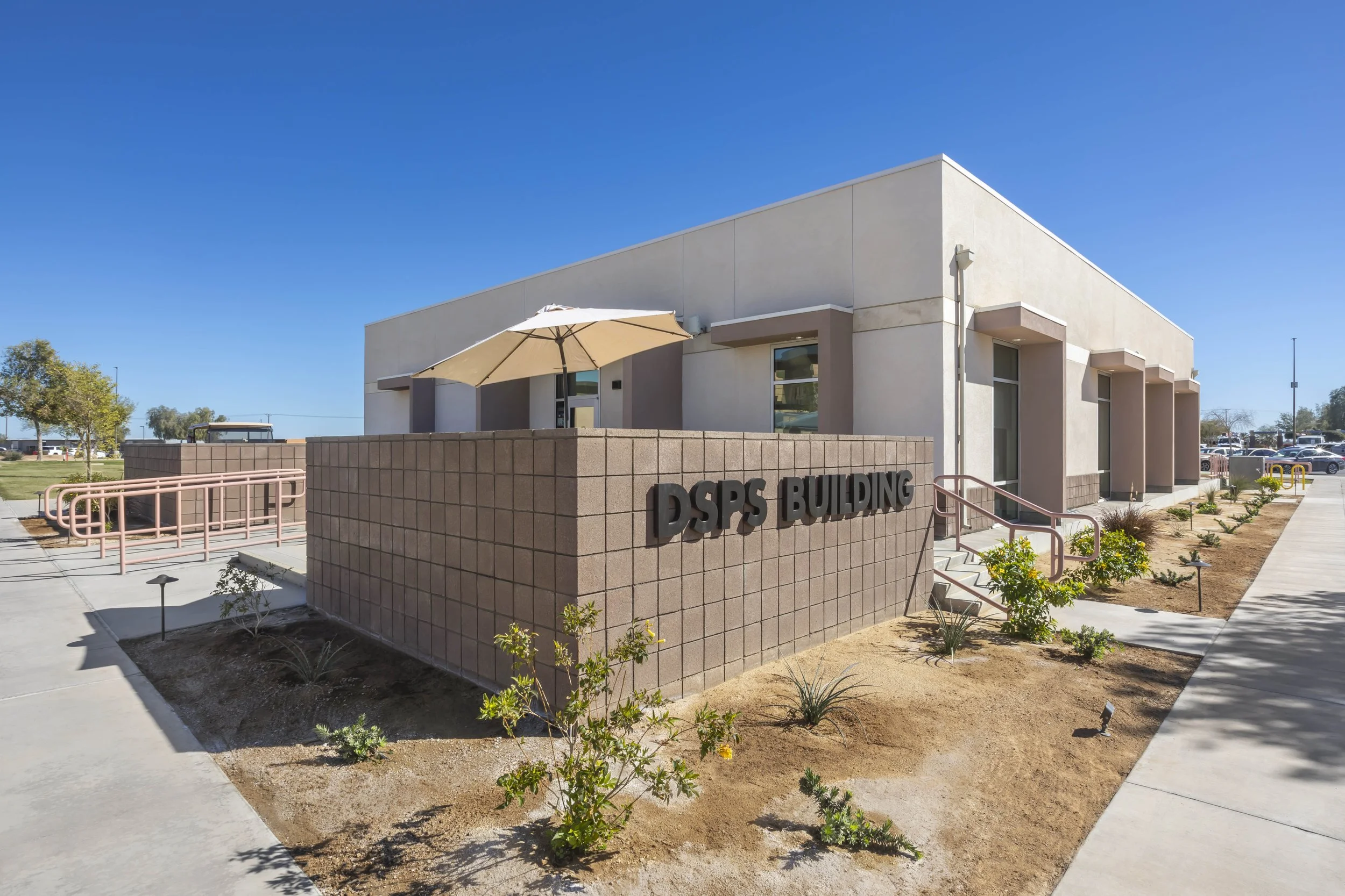 Exterior of the DSPS building with a beige wall and landscaping under a clear blue sky.