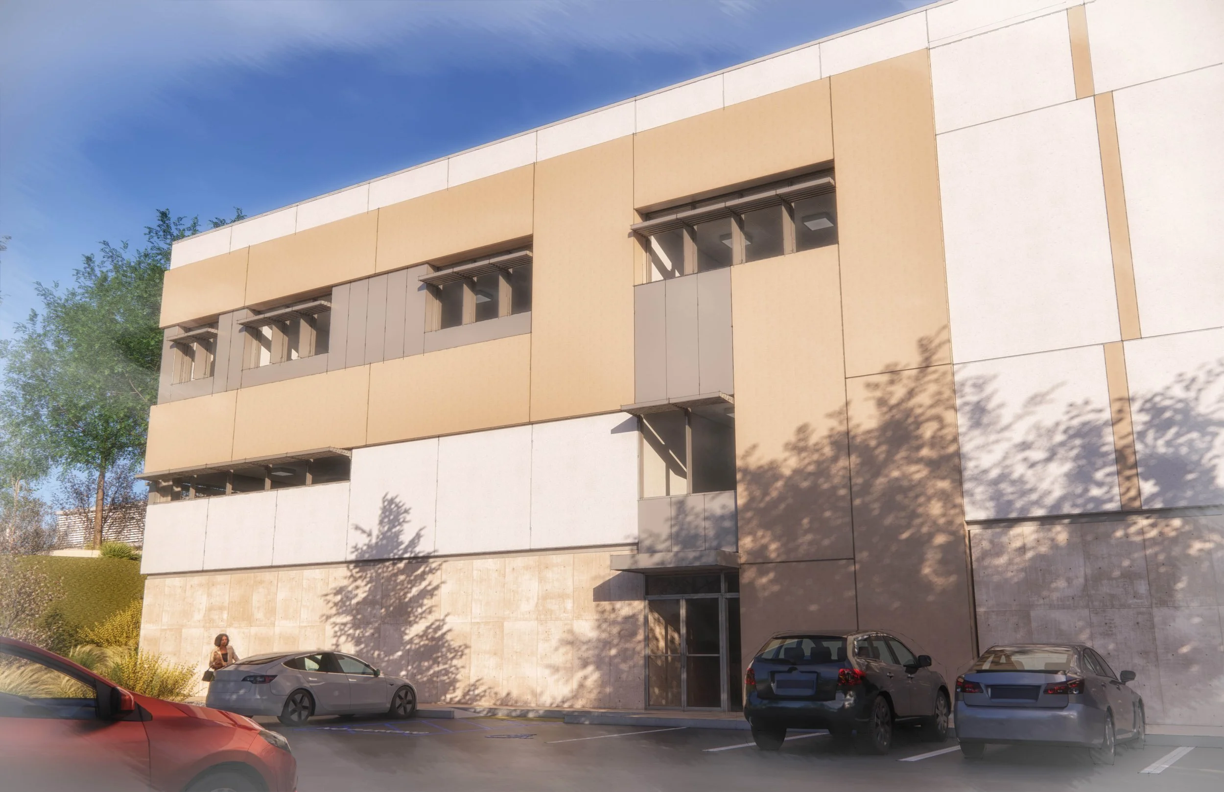 Modern multi-story building with beige and white panels, parking lot with several parked cars, a woman walking on sidewalk, trees casting shadows, and a partly cloudy sky.