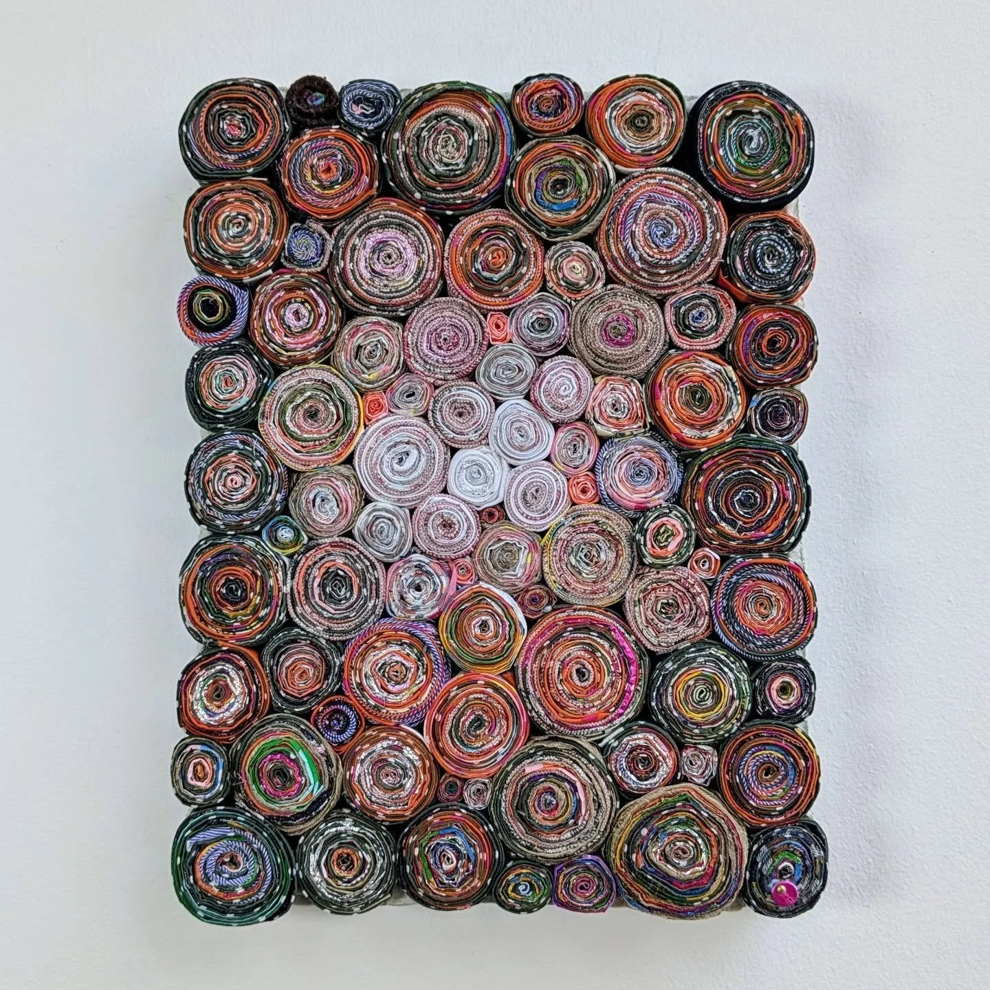 Janis, 2025. 100% waste: used hairdresser&rsquo;s foils, toilet paper wrap and leftover fabric (23x30cm).
A patchwork jumpsuit shimmering with orange, pink and sage green, their polka-dotted ensemble standing out. Spotted repurposing discarded jewel