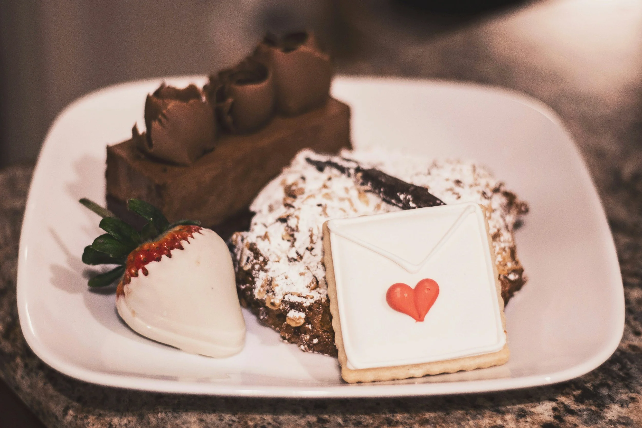 A plate of valentines treats: chocolate cake, cookies, chocolate covered strawberry.