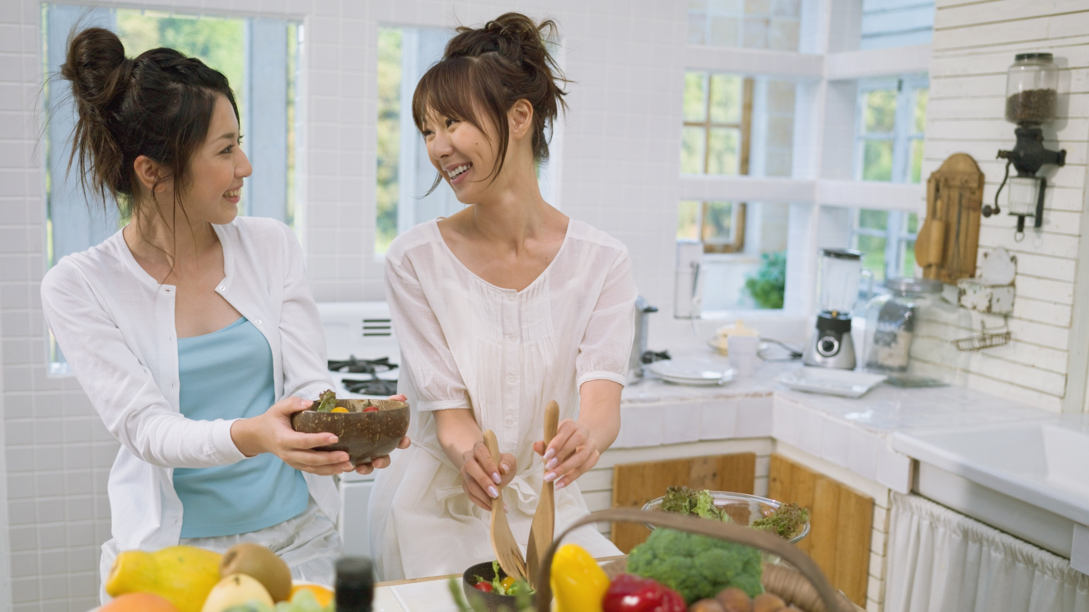 Women in kitchen cooking a healthy meal together.