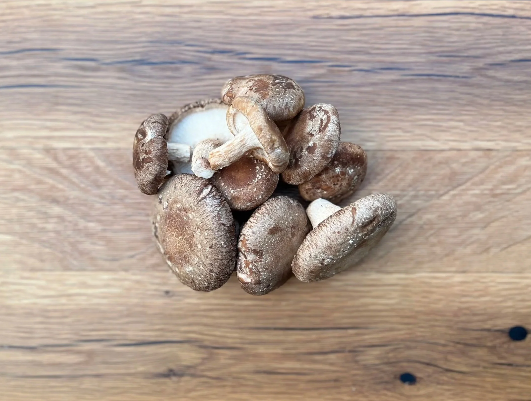 A group of fresh brown mushrooms on a wooden surface.