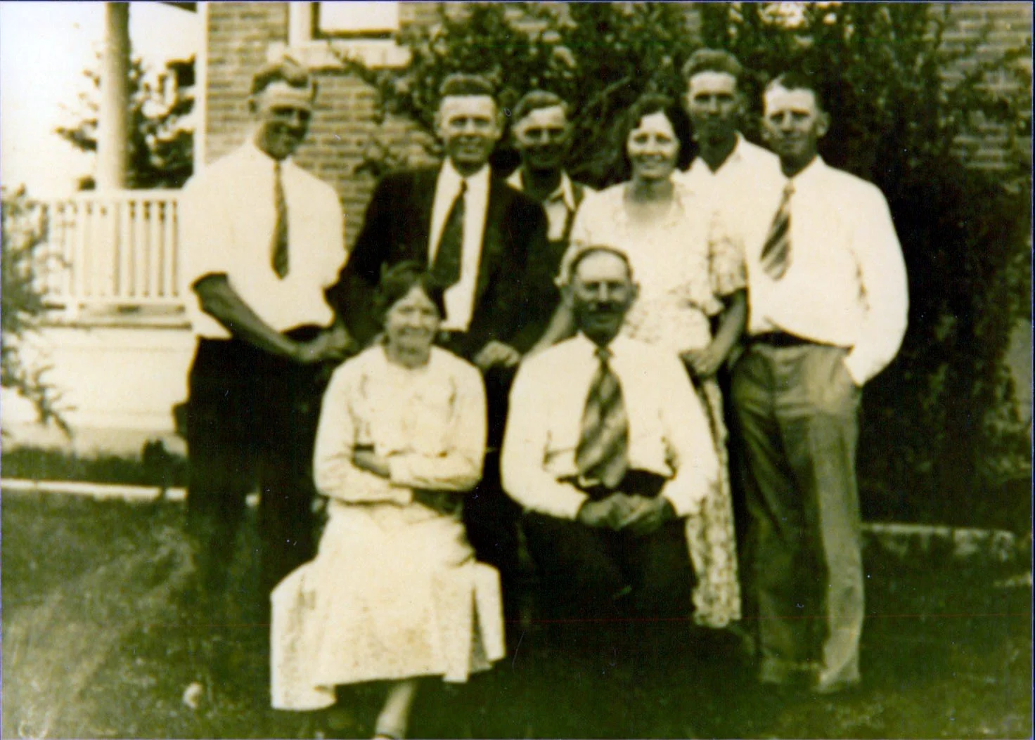 John and Marie Schmidt with their six children dressed in formal clothes posing in front of their house in West Jordan, Utah.