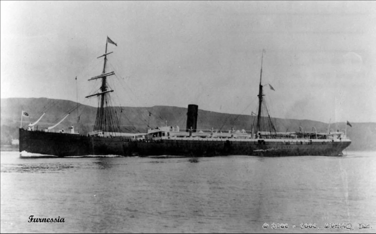 Historical black and white photograph of the steamship Tunnessia with two masts and a smokestack, sailing on the water with hills in the background.