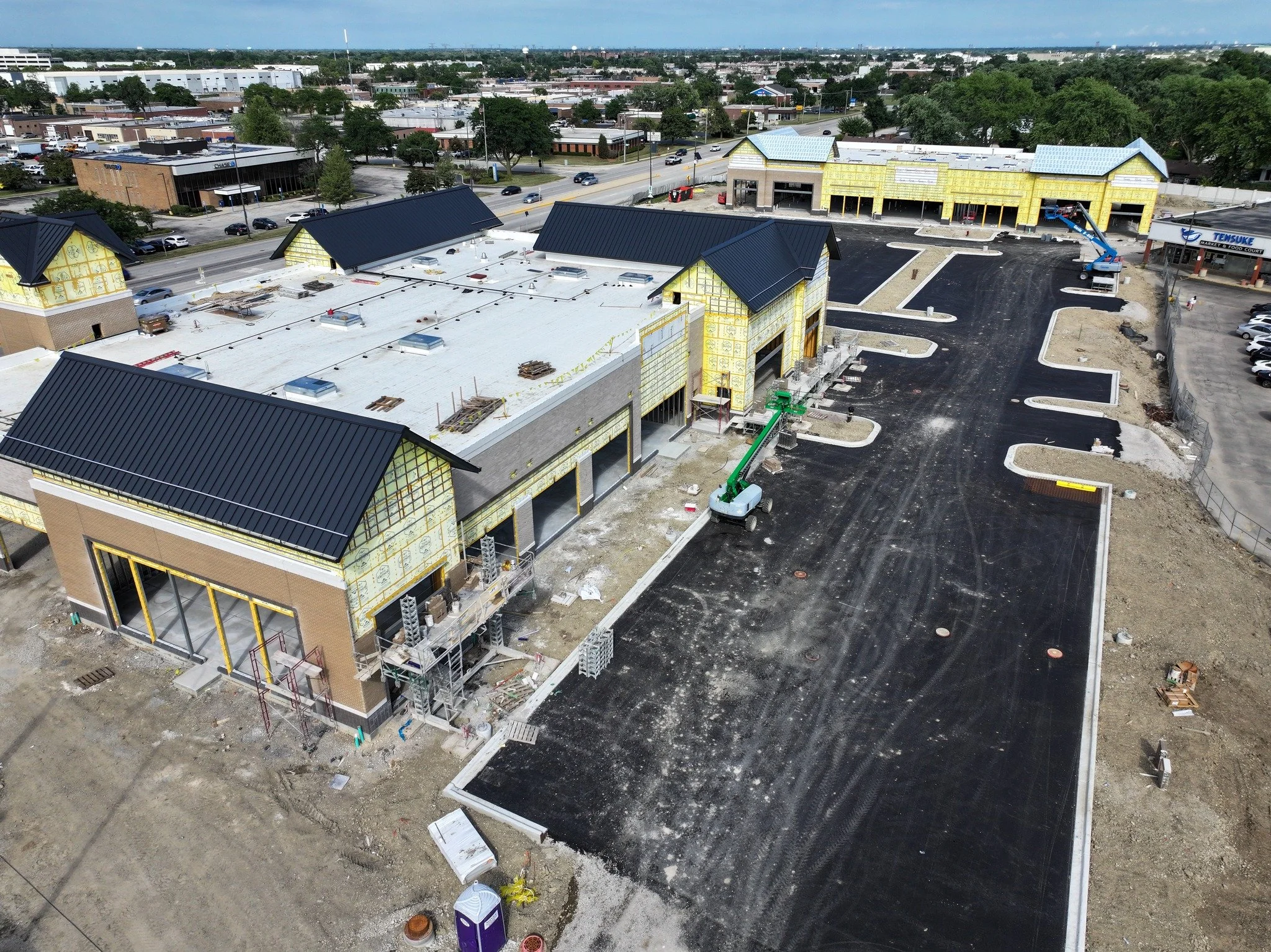 The VUE–Elk Grove Village is moving right along! The parking lot is taking shape with new curbs and asphalt, while masonry and exterior sheathing move ahead on both buildings.
Next up: storefront installation and tenant build-outs for 7 Mile C