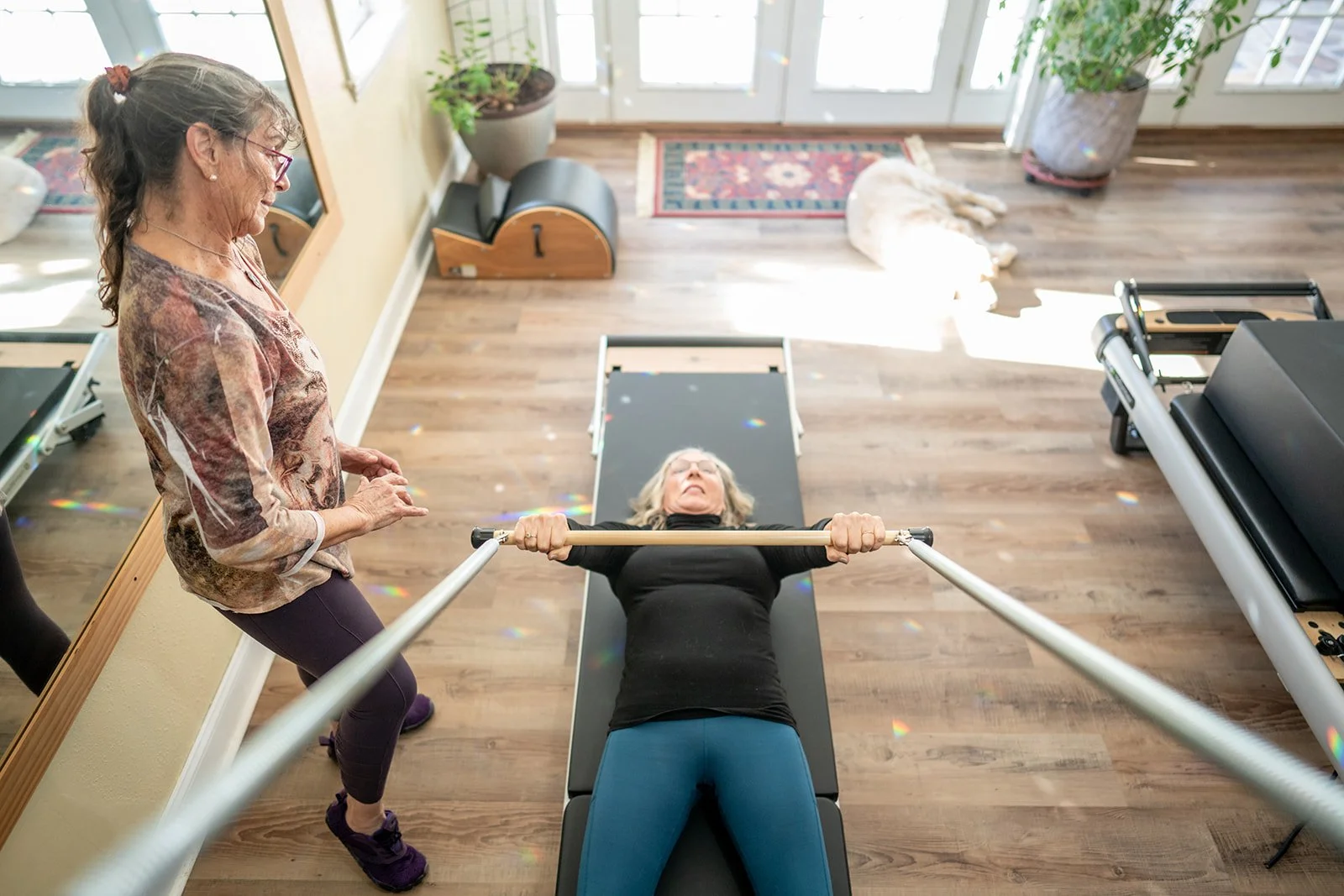 Kyra Russell guiding a client on the Pilates reformer in her light-filled studio