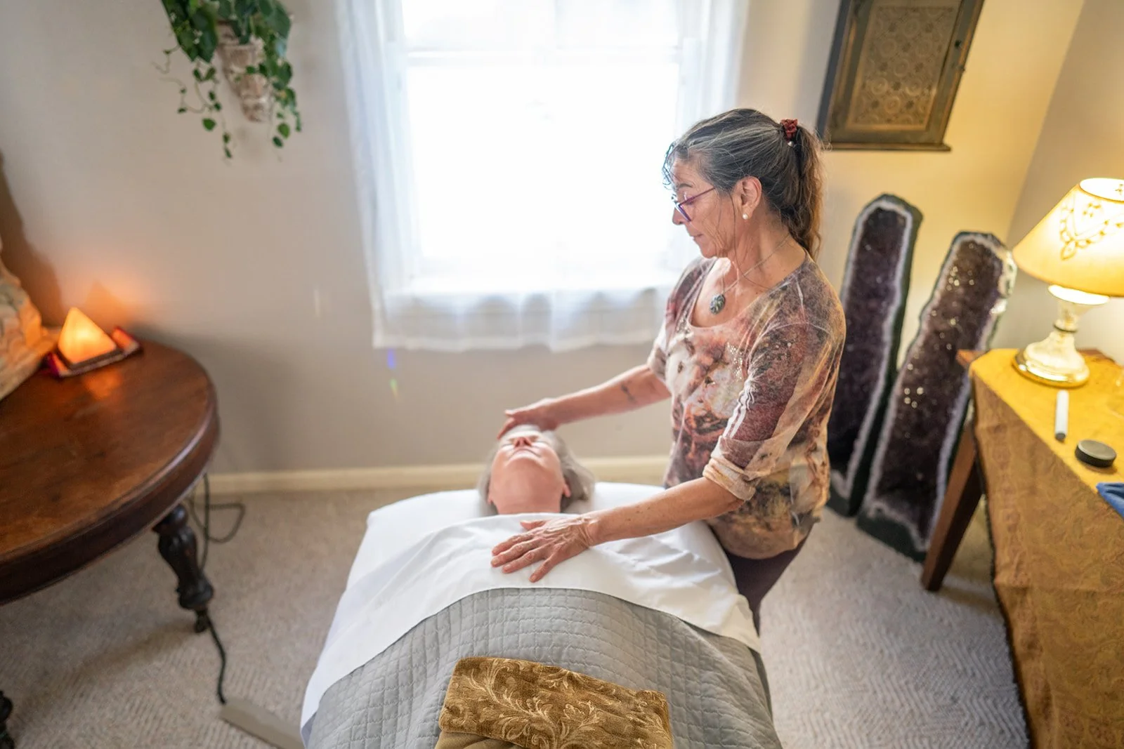 Kyra Russell resting her hands gently on a client in a calm treatment room