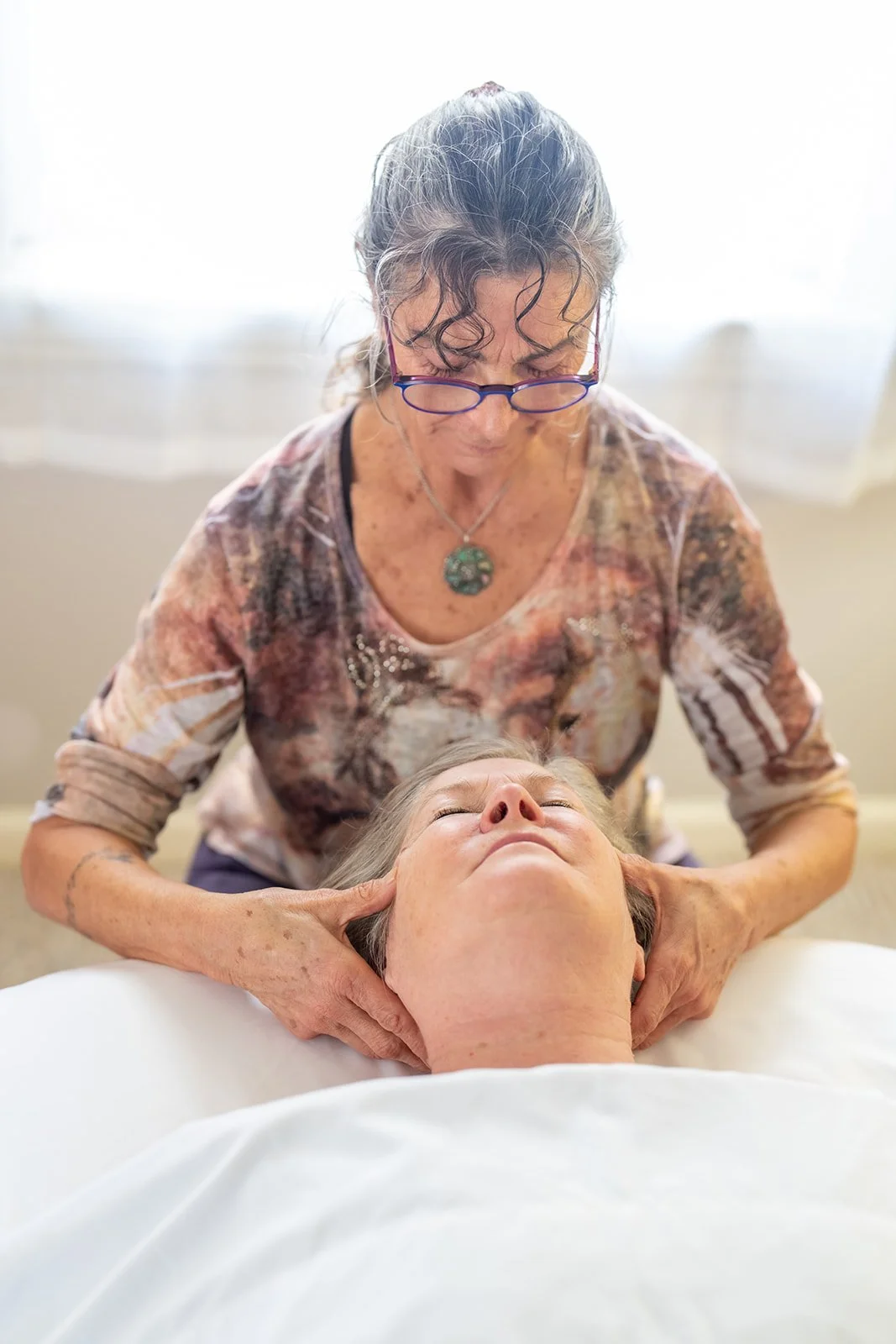 Kyra Russell gently cradling a client’s head and neck during a recovery session
