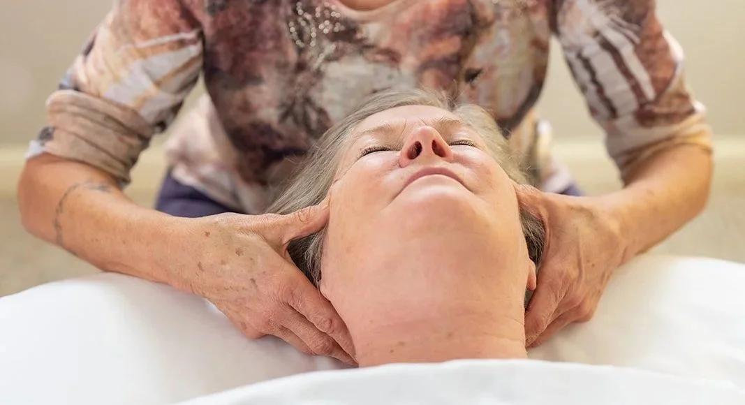 Kyra Russell’s hands gently cradling a client’s head during a calm recovery session