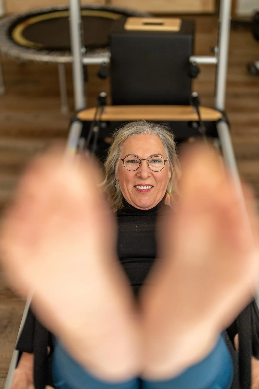 A smiling Pilates client with her feet up toward the camera