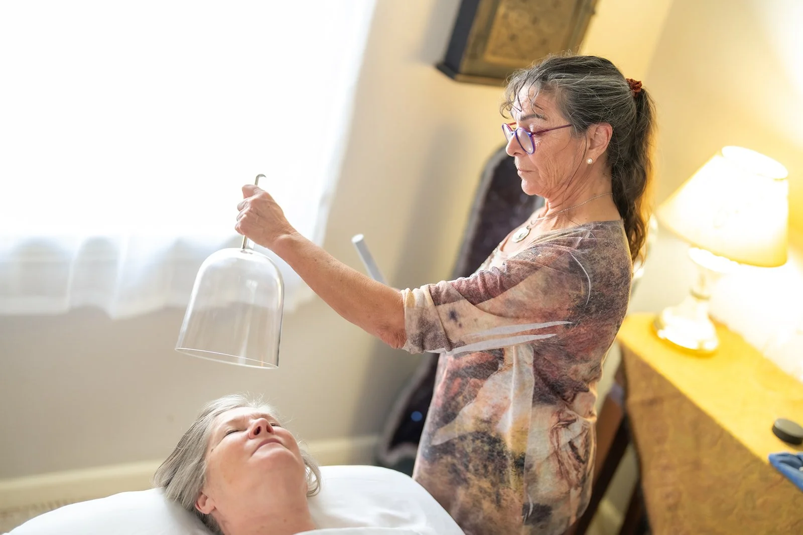 Kyra holding a crystal singing bowl over a client during an energy session