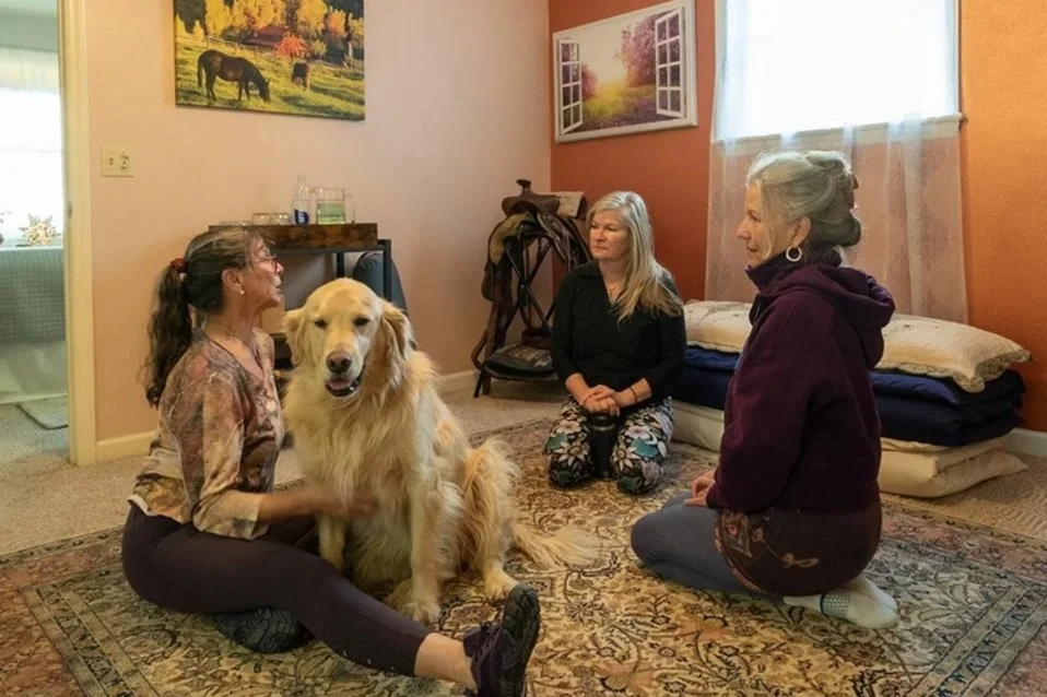 Kyra Russell sitting on the studio rug with her golden retriever and two guests