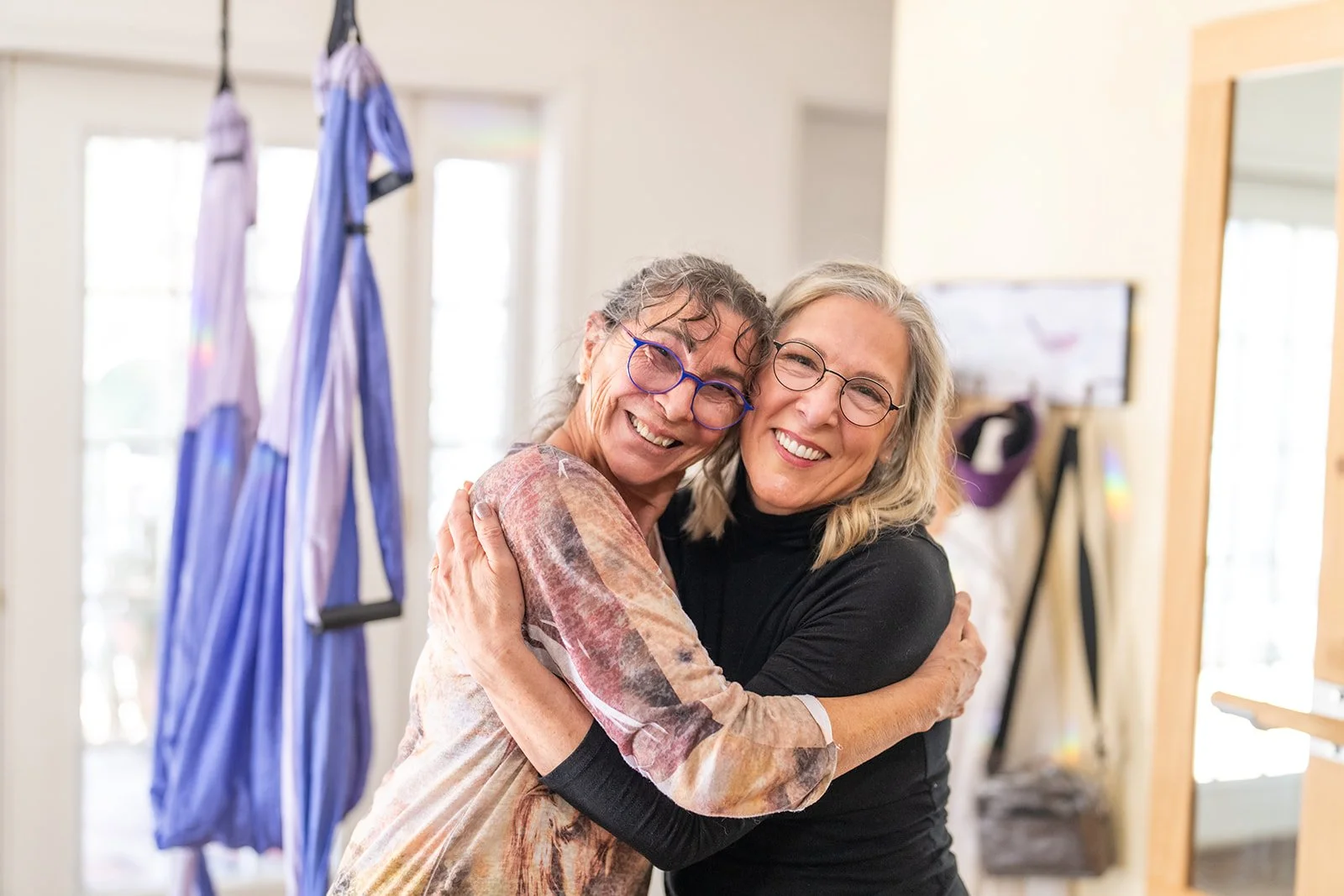 Kyra Russell sharing a joyful hug with a client in her studio