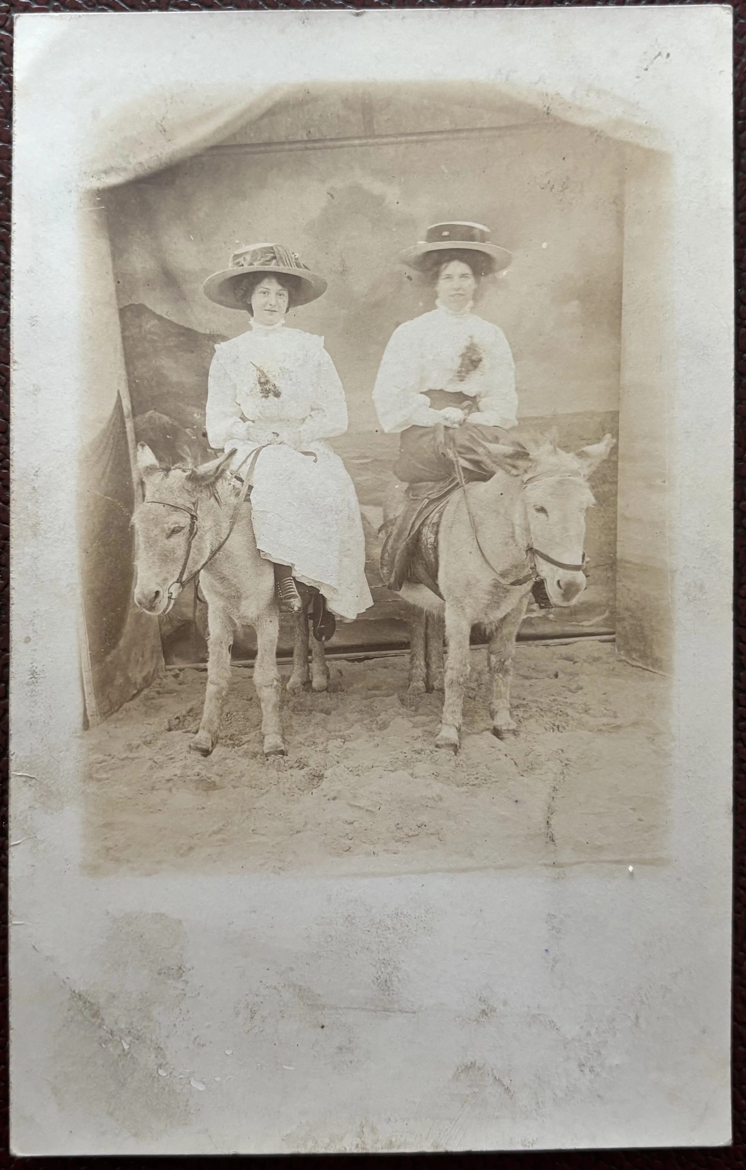 Postcard portrait of two women sitting on donkeys on the beach by Scarborough Photographer Robert Harrison
