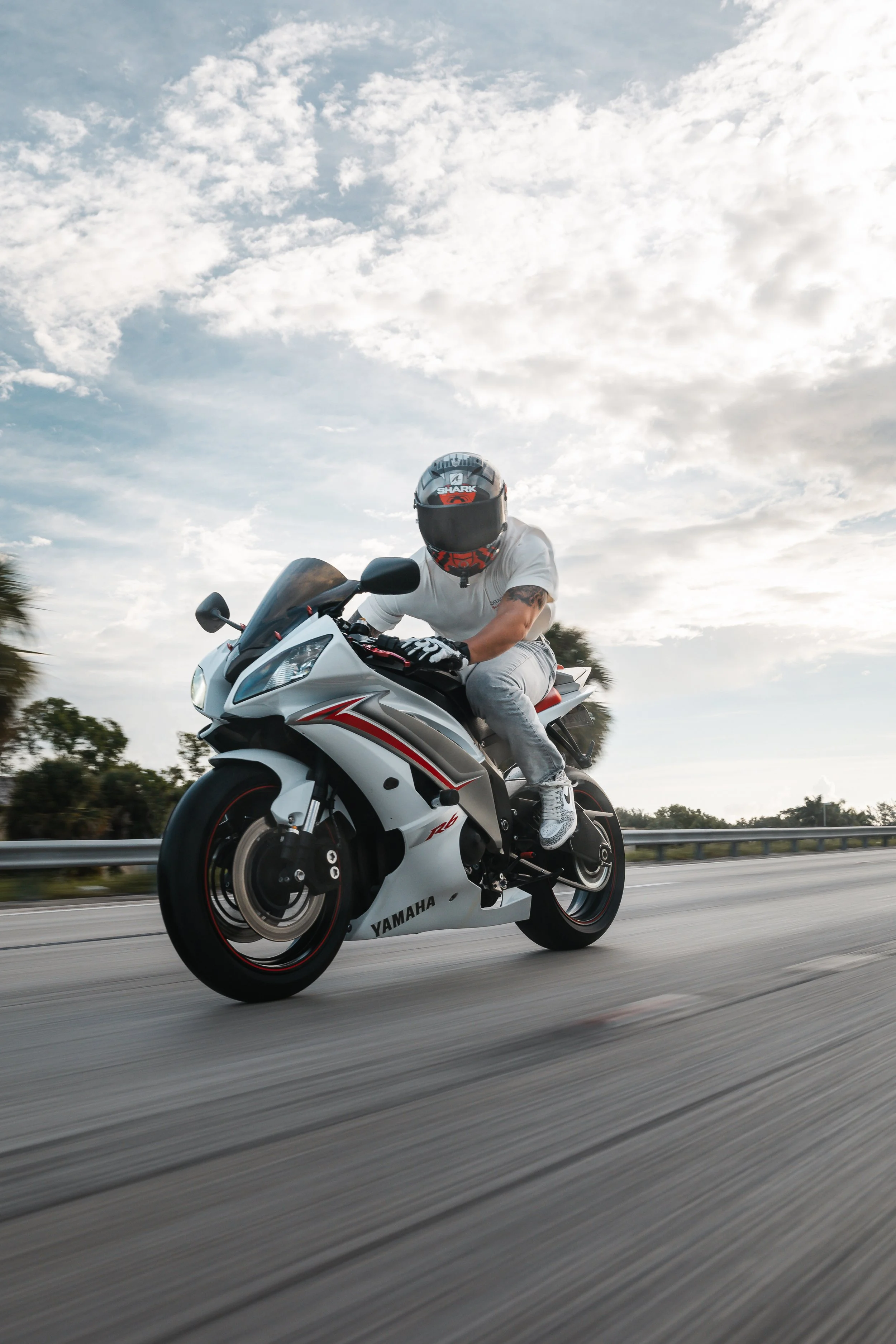 Motorcyclist riding a Yamaha sportbike on the highway with a cloudy sky in the background.