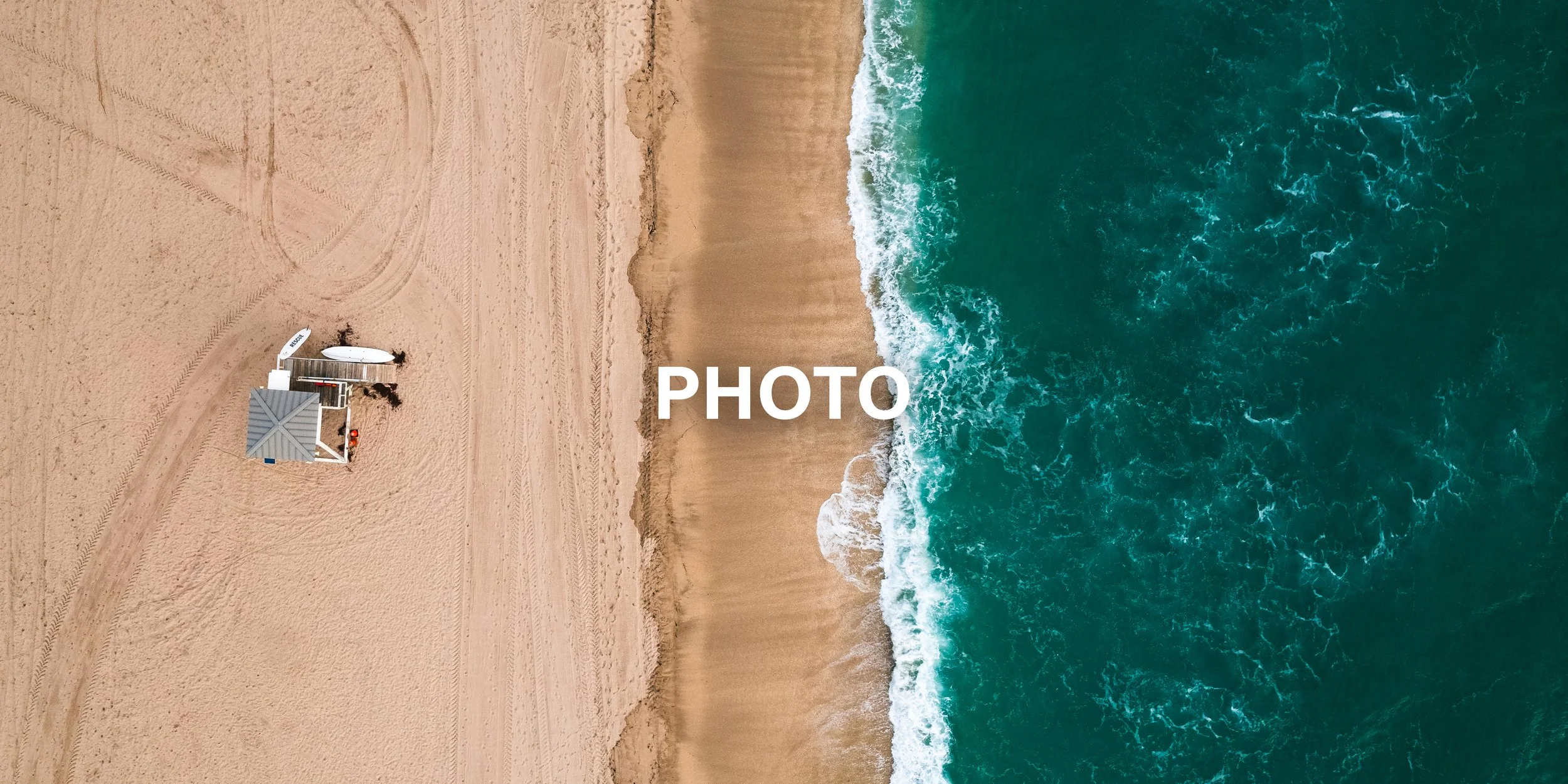 Aerial view of a sandy beach with a small shelter and two paddleboards, next to the ocean with waves.