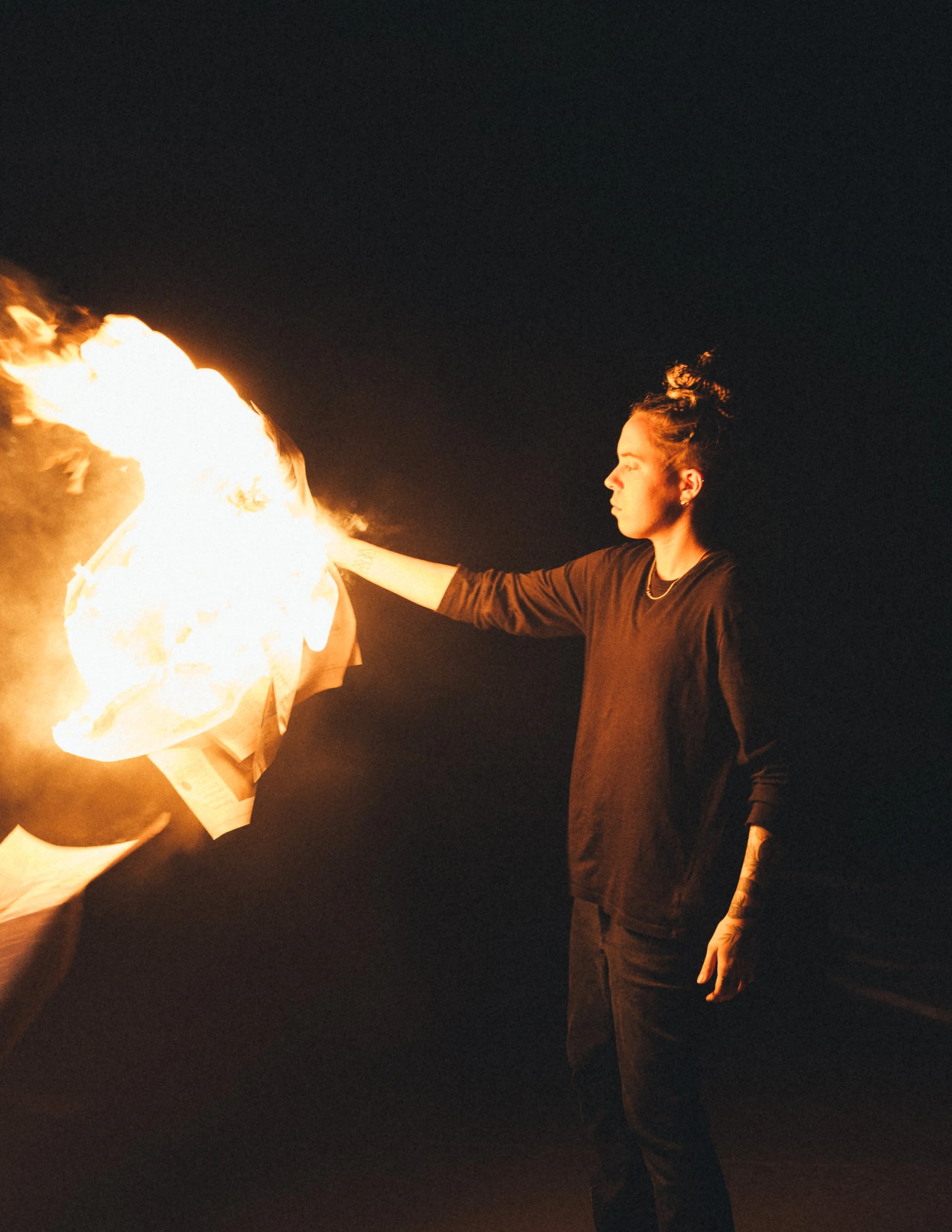 Person holding a fireball during a night fire performance or stunt.