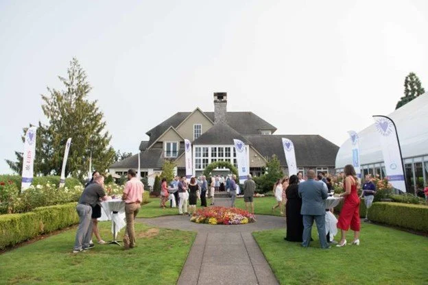Group of adults stand on the front lawn of the Oregon Golf Club.