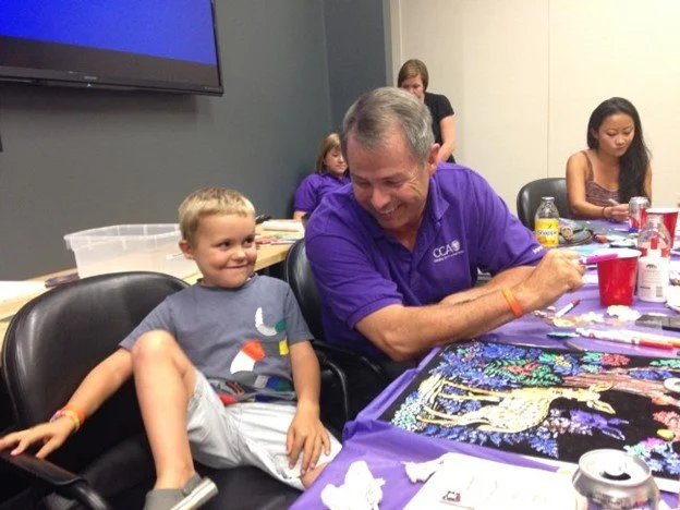 Young boy sits in a chair next to his JoyRx Mentor.