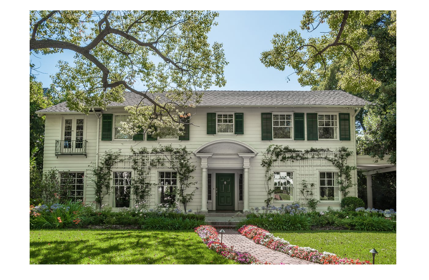 white colonial house with floral walkway