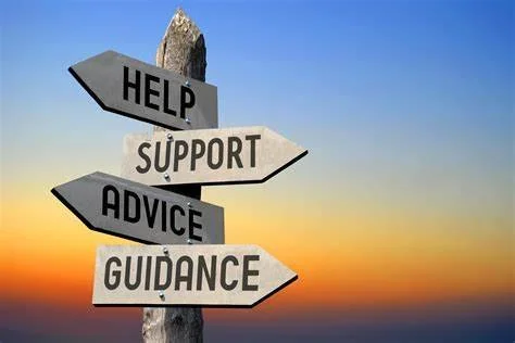 Signpost with arrows labeled 'Help,' 'Support,' 'Advice,' and 'Guidance' against a sunset sky.