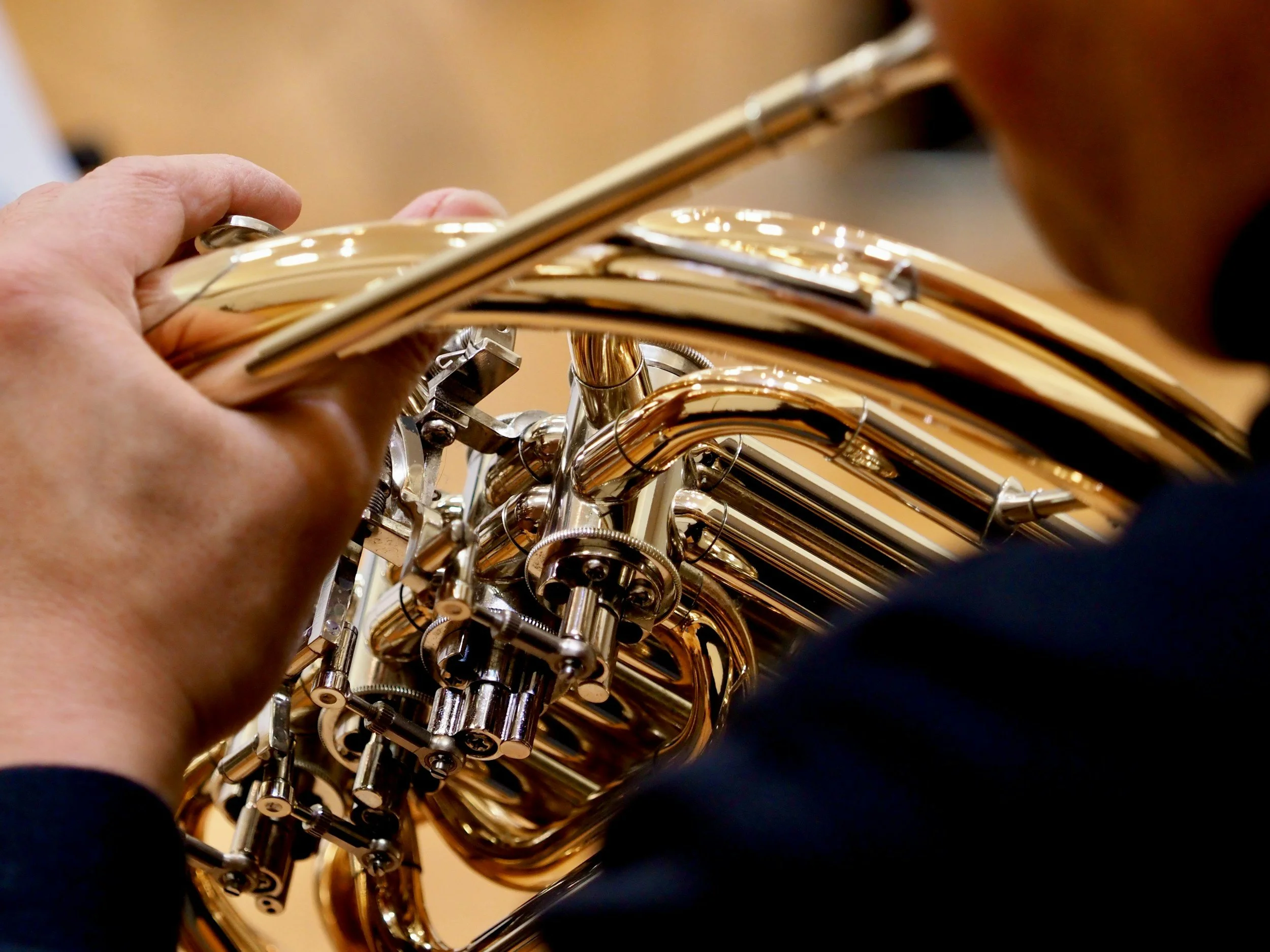 Adult playing the French horn in a French horn lesson