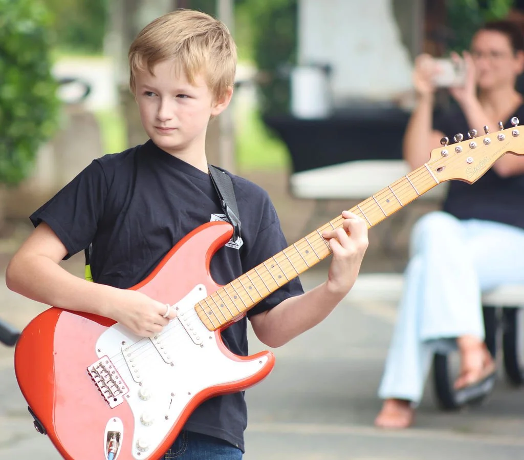 Student guitarist performing with a student rock band in the Learn Music Legends program in Cornelius, NC