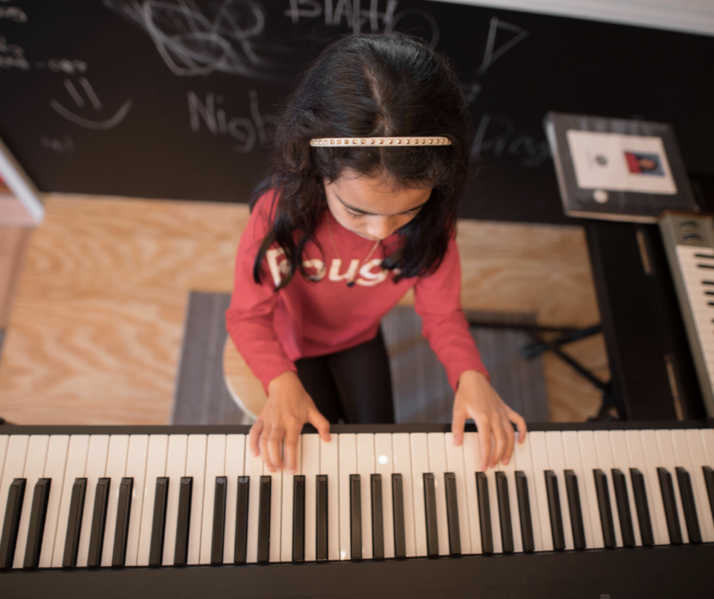 Preschool age girl playing piano at a Little Legends class in Cornelius, NC