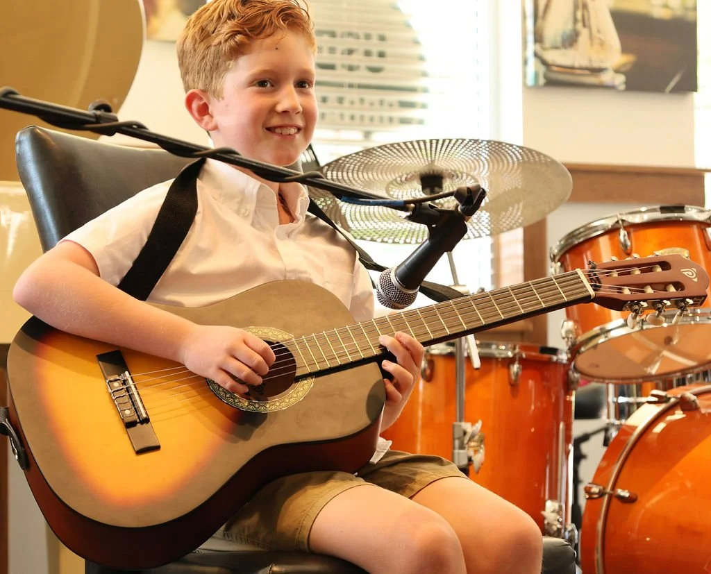 Student playing guitar at a Learn Music Live recital in Huntersville, NC