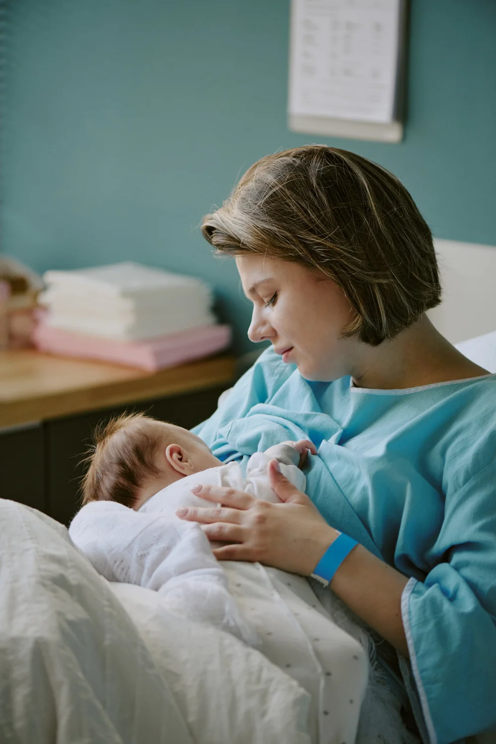 A mother gently cradling her newborn in a hospital room.
