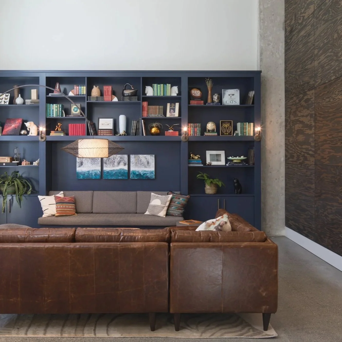 Modern lounge with large windows, gray and beige furniture, decorative partitions, and a decorative wall art.