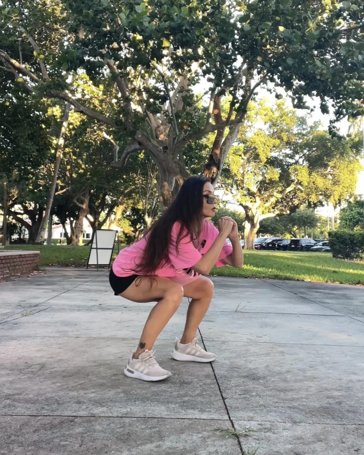 Woman in a squat position during an outdoor sunset workout at George English Park in Fort Lauderdale