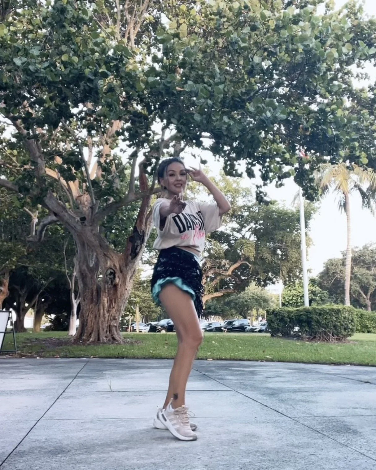 Woman dancing outdoors at George English Park during a belly dance fitness class, demonstrating a low-impact dance move in Fort Lauderdale, FL