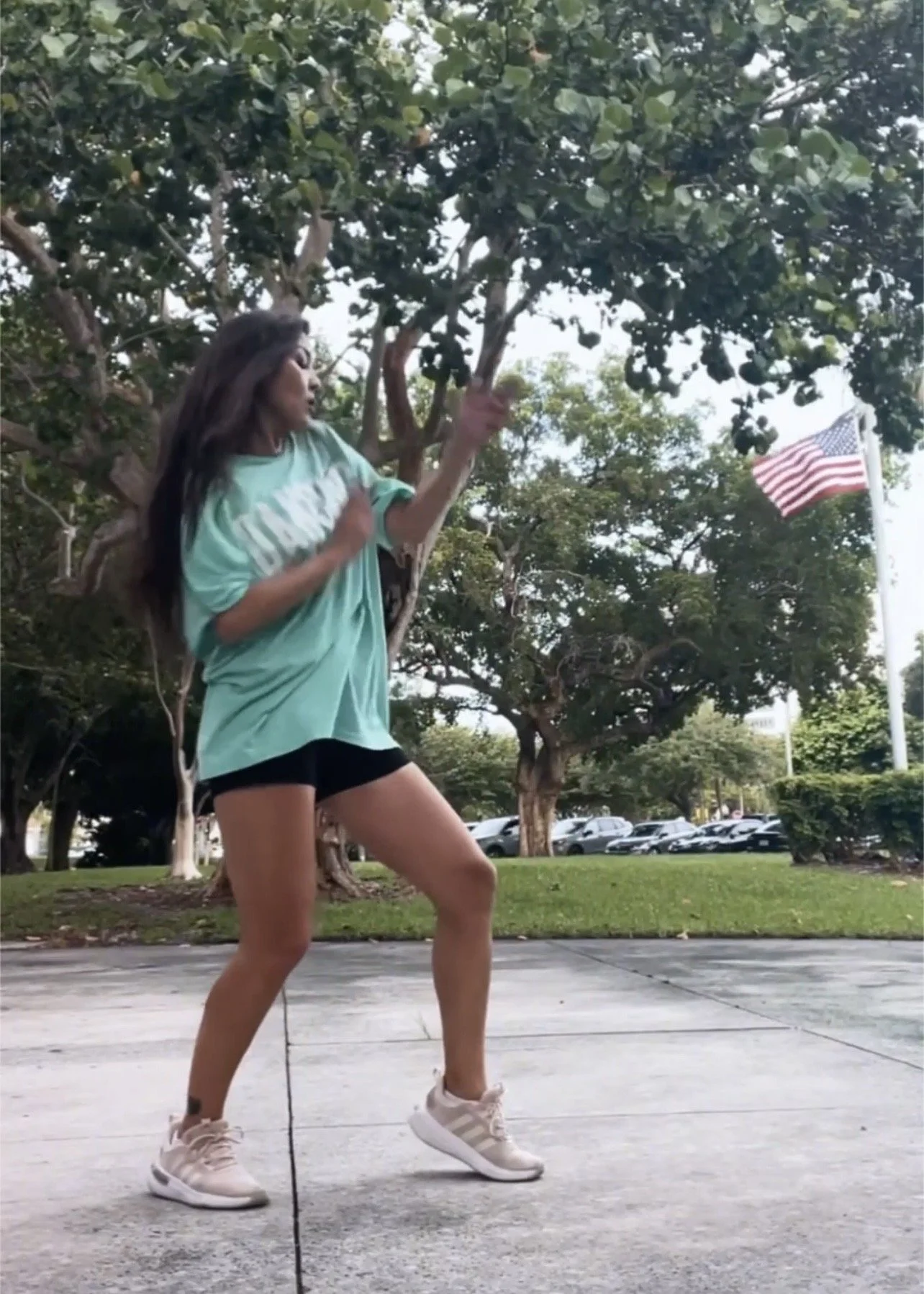 Woman mid-movement during an outdoor belly dance fitness workout in a Fort Lauderdale park