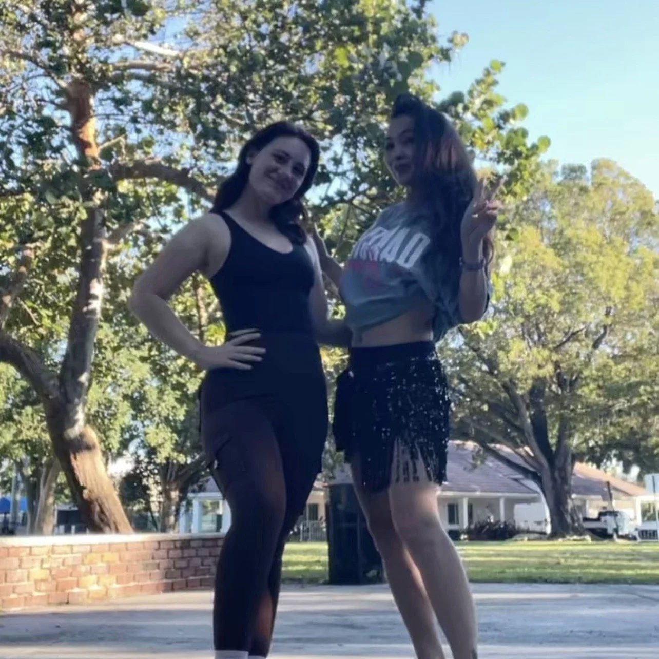 Two women in workout clothes and a fringe skirt standing outdoors at George English Park, Fort Lauderdale