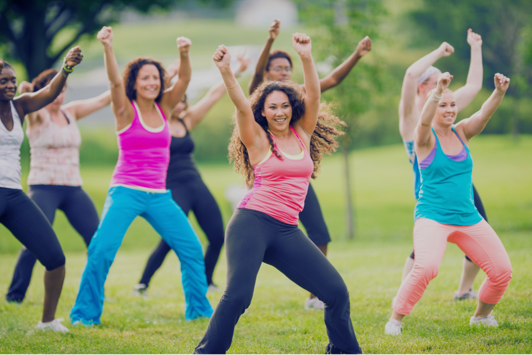 Group doing high-energy outdoor dance class, representing fast-paced Zumba-style workout