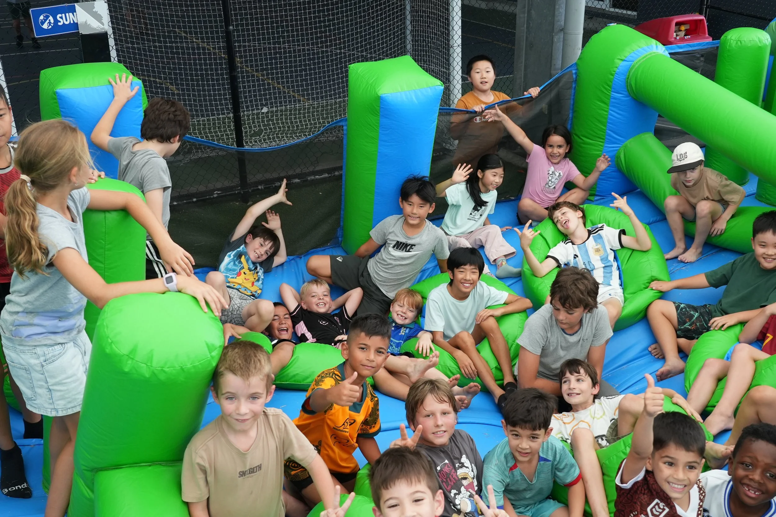 Children playing and sitting on an inflatable bounce house at a school playground.