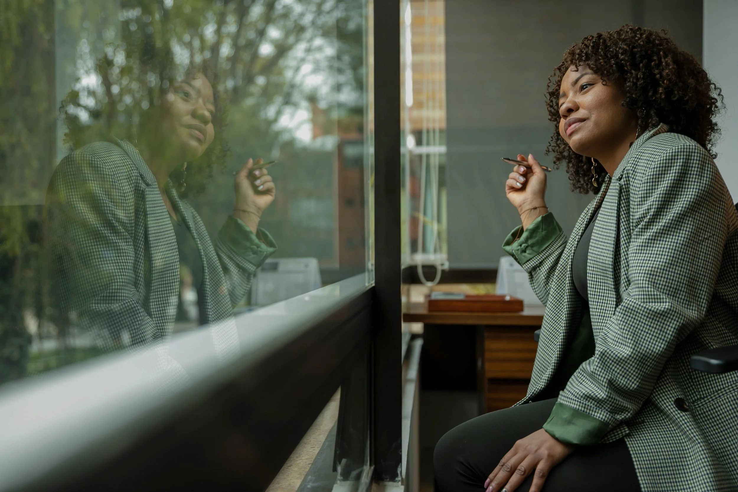 Woman sitting by a window reflecting thoughtfully — illustrating self-awareness and inner dialogue in the neuroplasticity process