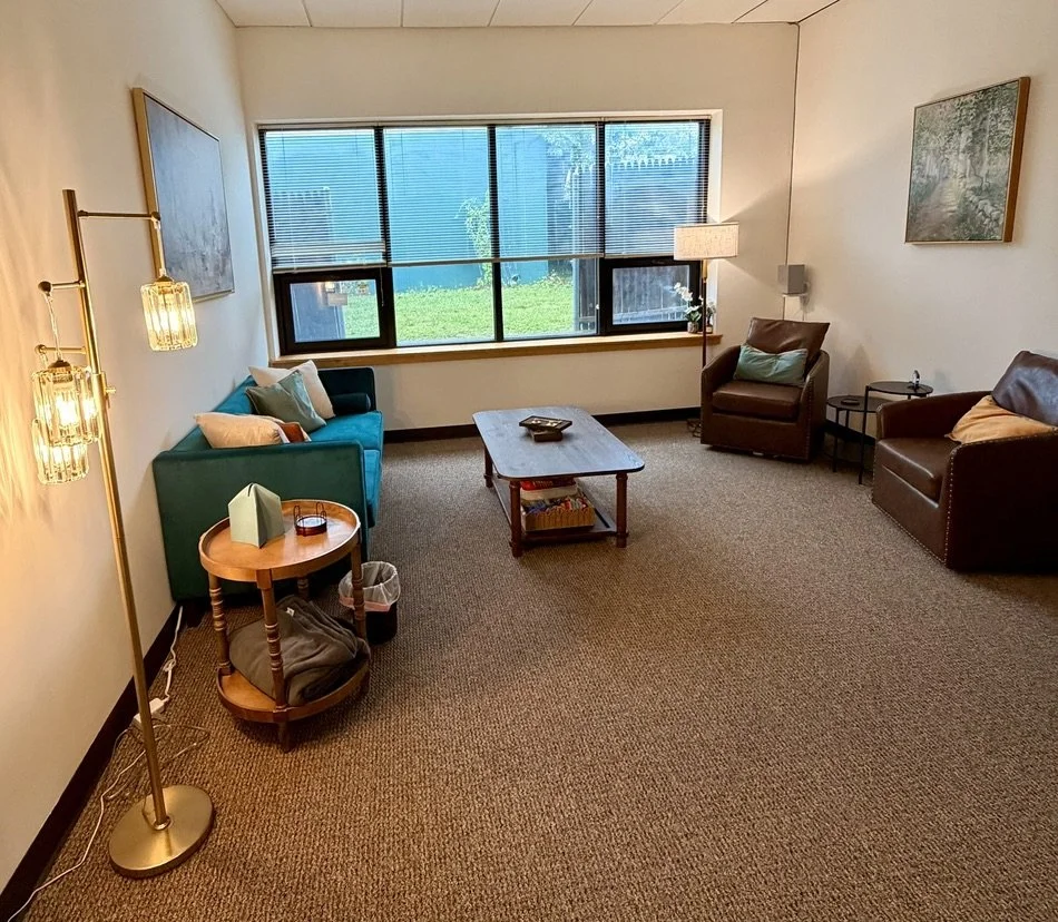 Port Washington therapy office with a sofa, coffee table and two armchairs by a large window