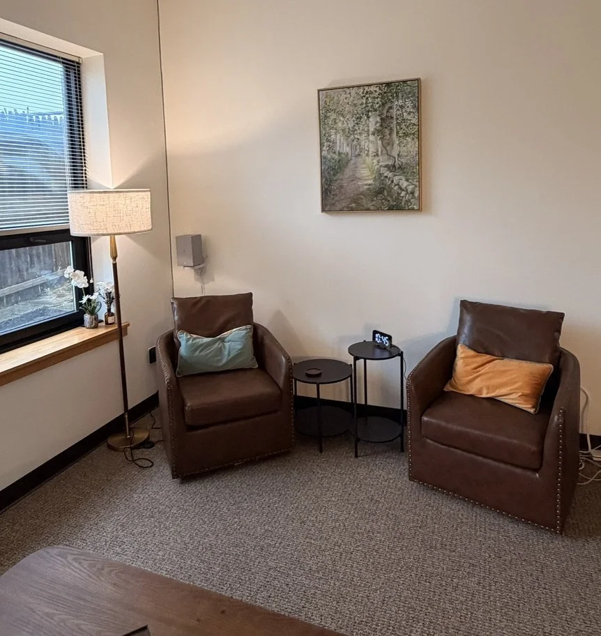 Two leather armchairs and a landscape painting in the Port Washington office