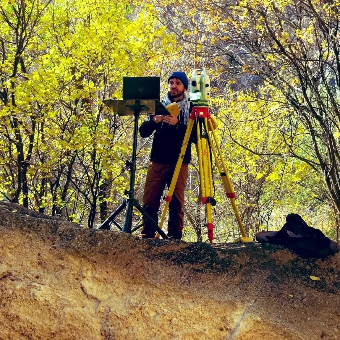 Dr Jayson Gill conducting archaeological survey work using surveying equipment in the field