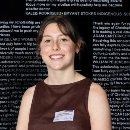 A young woman with brown hair and a friendly smile in front of a black background filled with white text.