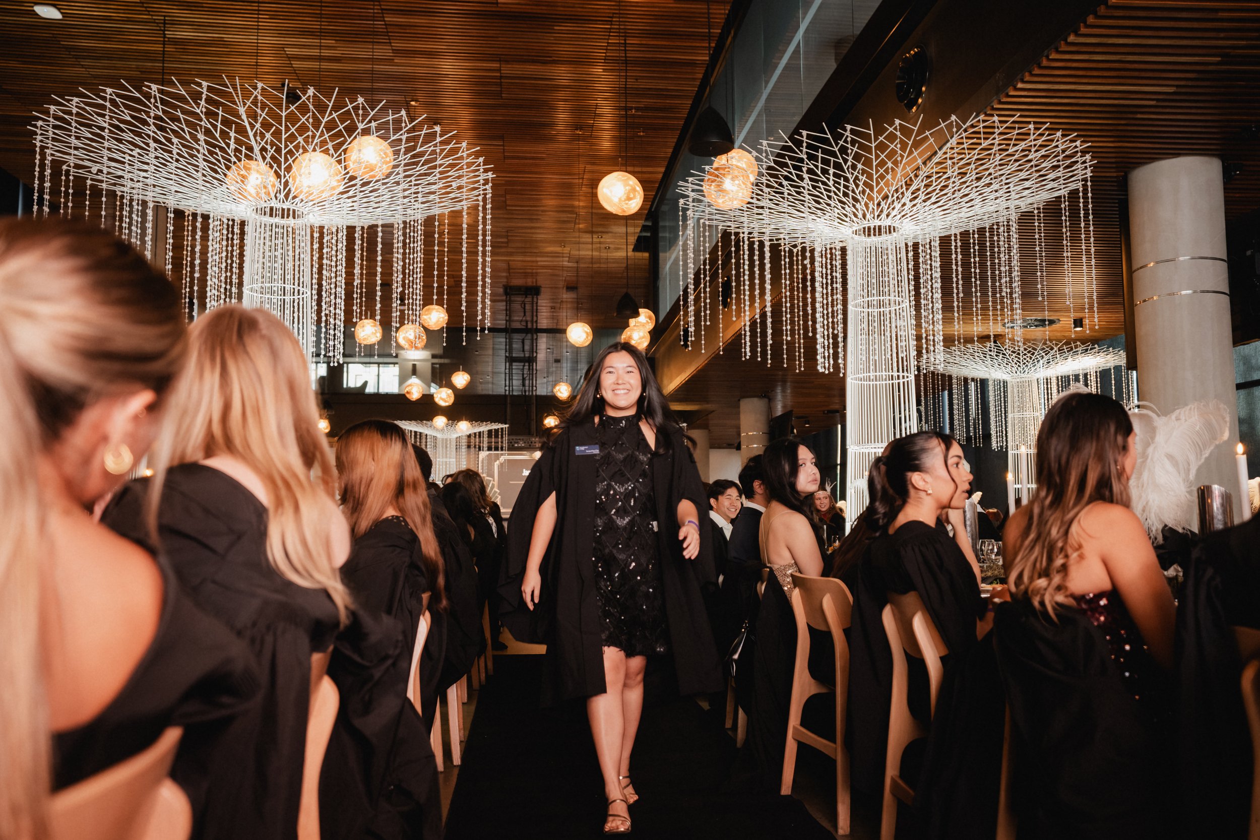 Curtin valedictorian and Resident Assistant Jacqueline Chu walking between guests at St Catherine’s College’s 2026 Roaring Twenties Valedictory Dinner in Perth.