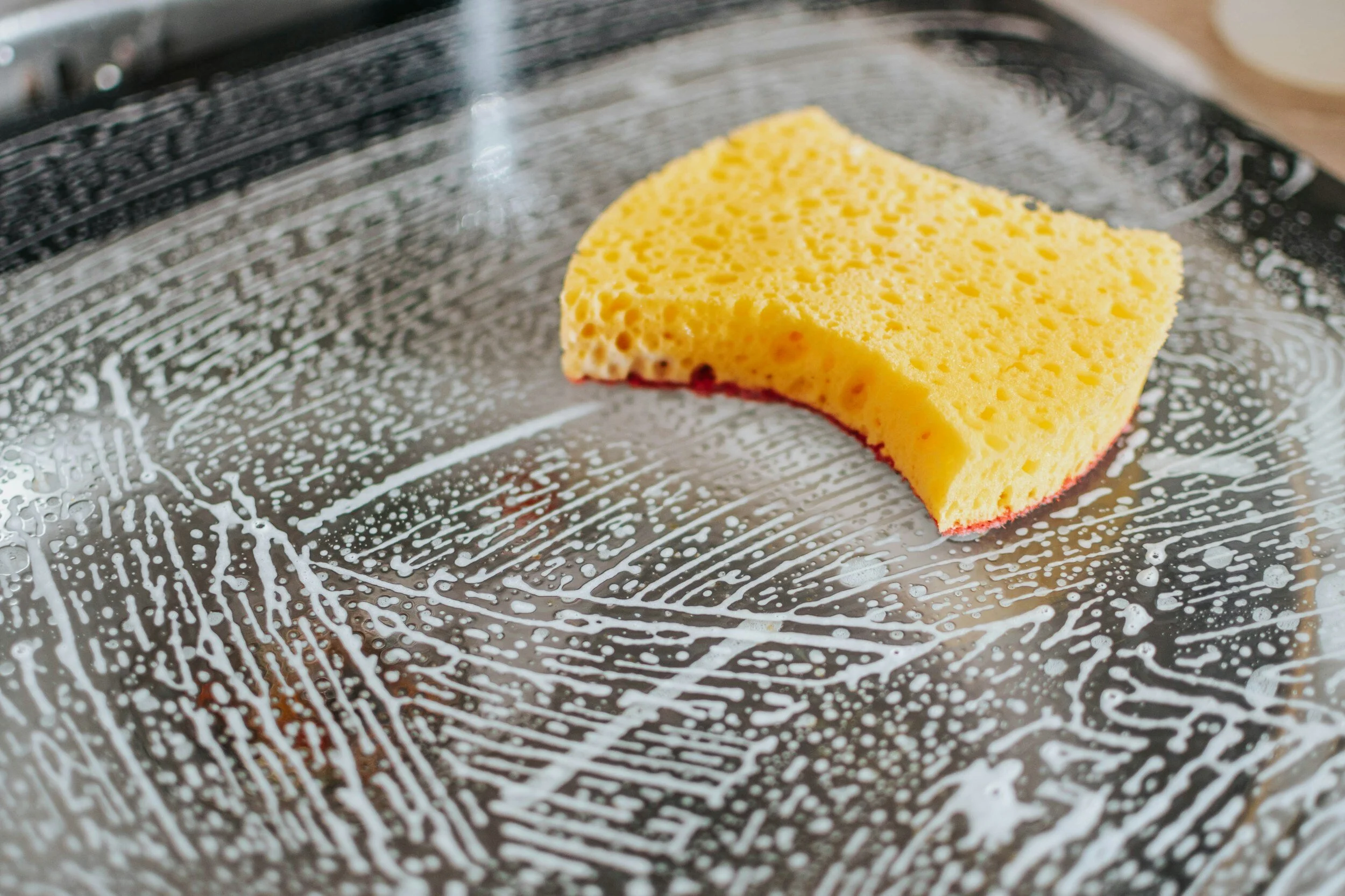 Image of an oven being cleaned with a yellow sponge