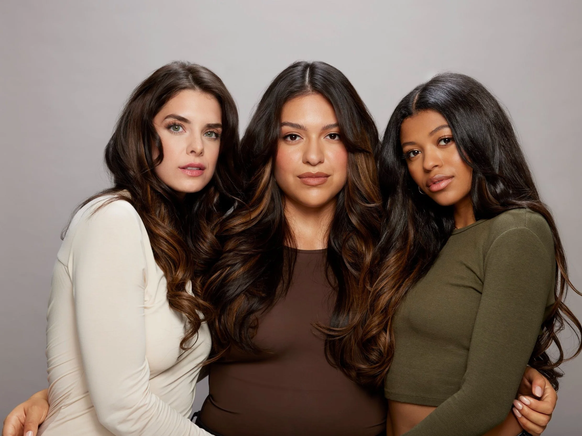 Three women wearing brown clip-in hair extensions