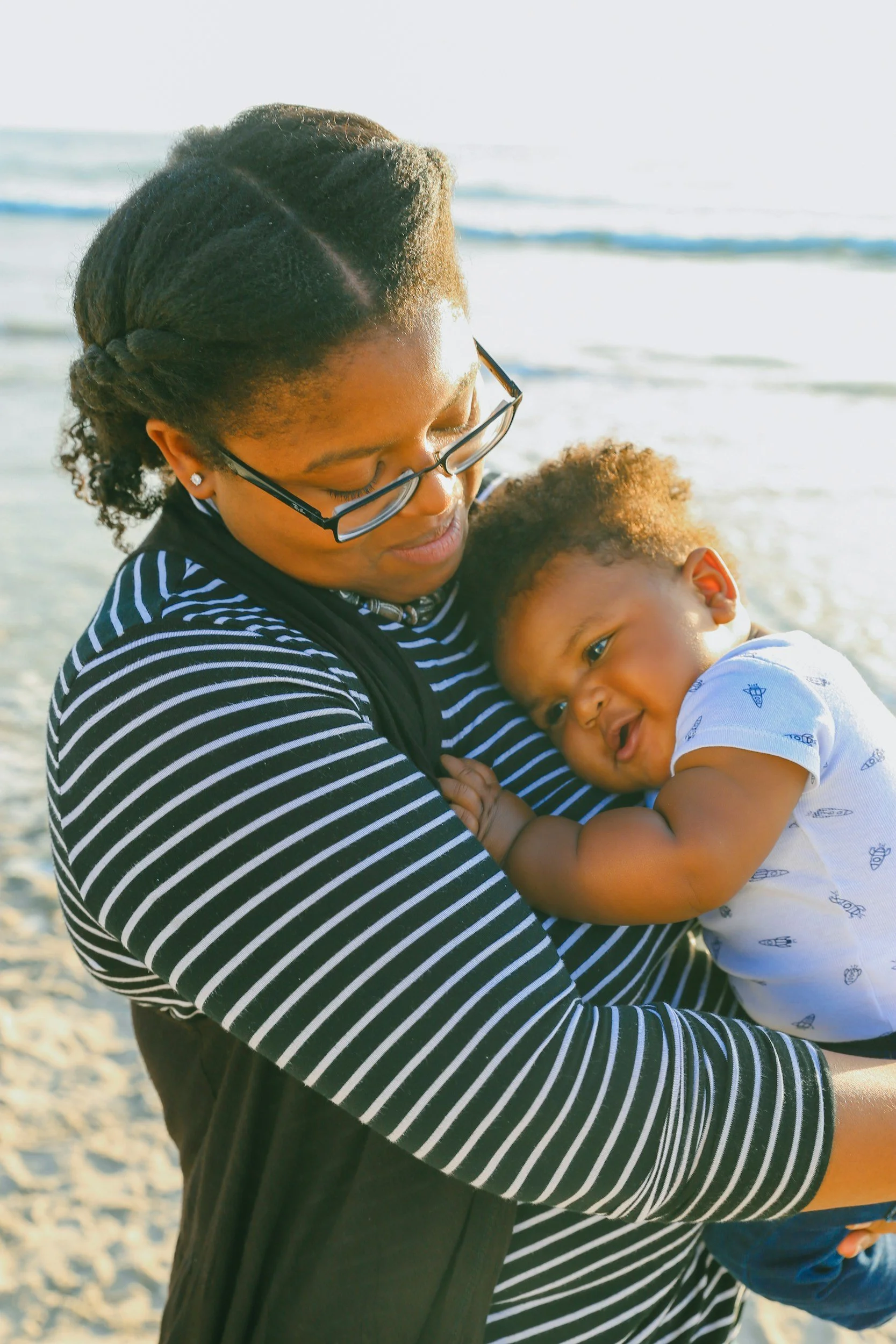 Mother holding a baby on a beach.