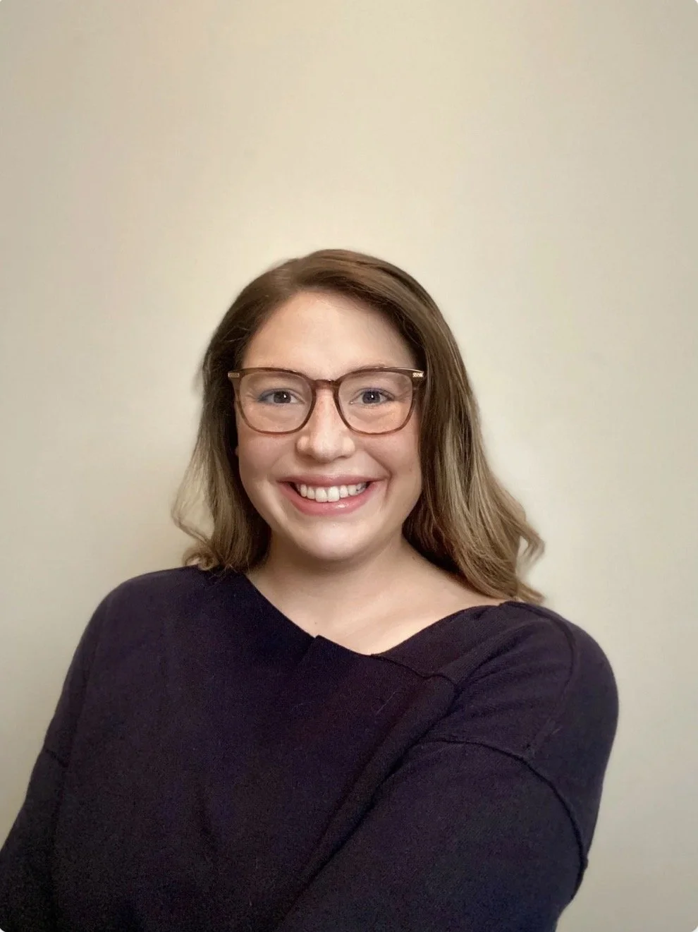 Smiling woman with black top and neutral background.