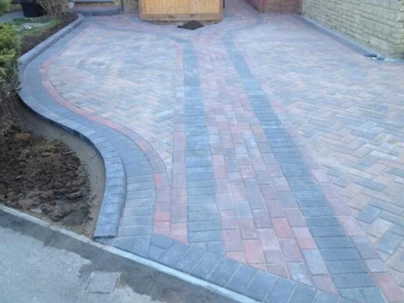 Newly paved driveway with a winding pattern of gray and reddish bricks, bordered with darker bricks.