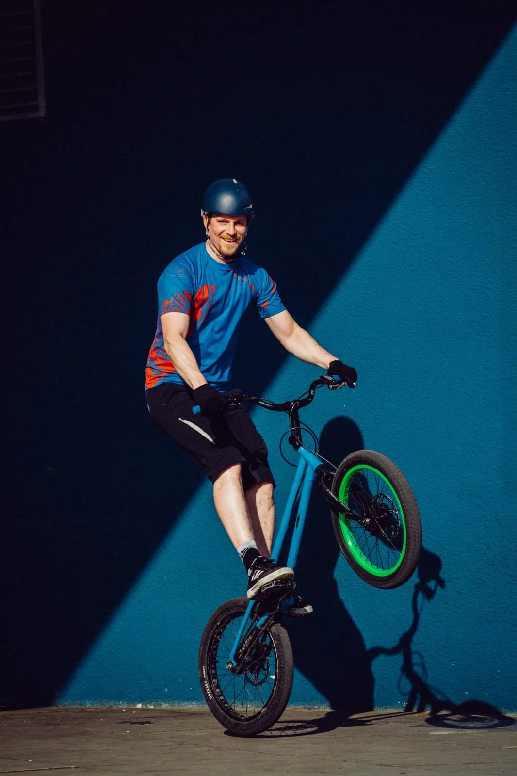 Mann trägt einen Helm und trägt auf einem Mountainbike im Fahrradtraining eine Radfahroutfit, während er einen Trick vollführt.